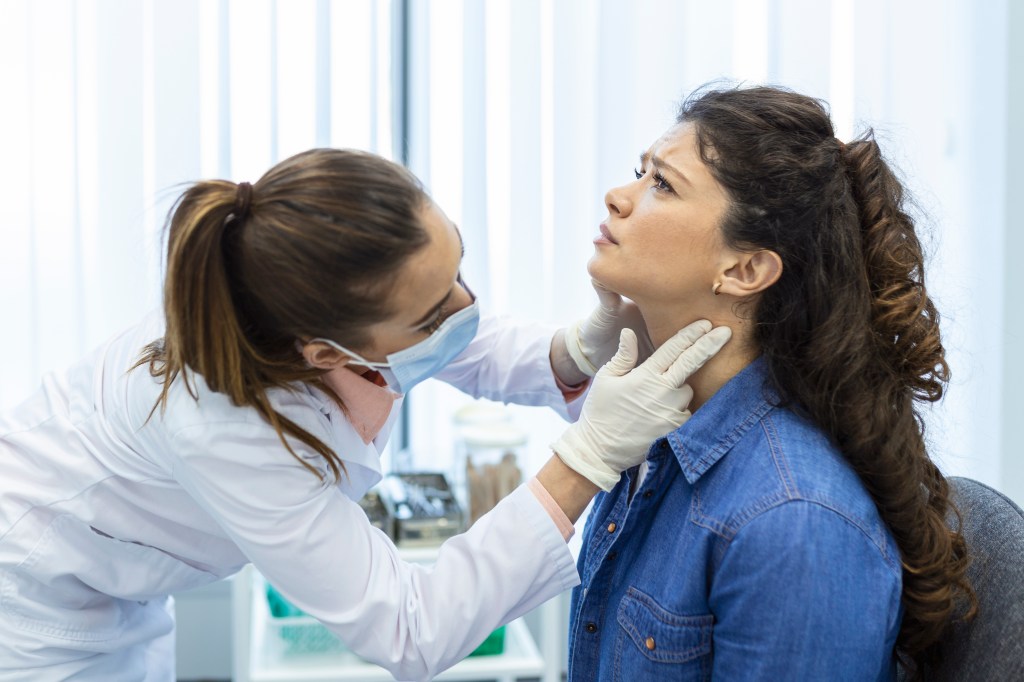 Médico examinando el cuello de una paciente en un consultorio.